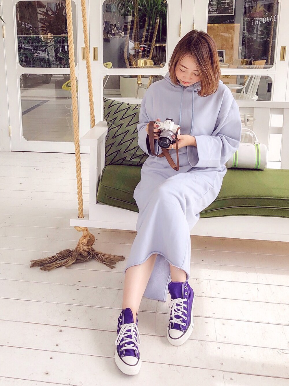 ブルー系のワンピース、パープル系のスニーカー、ホワイト系のハンドバッグを着用したレディースの秋コーディネートの1枚目の写真