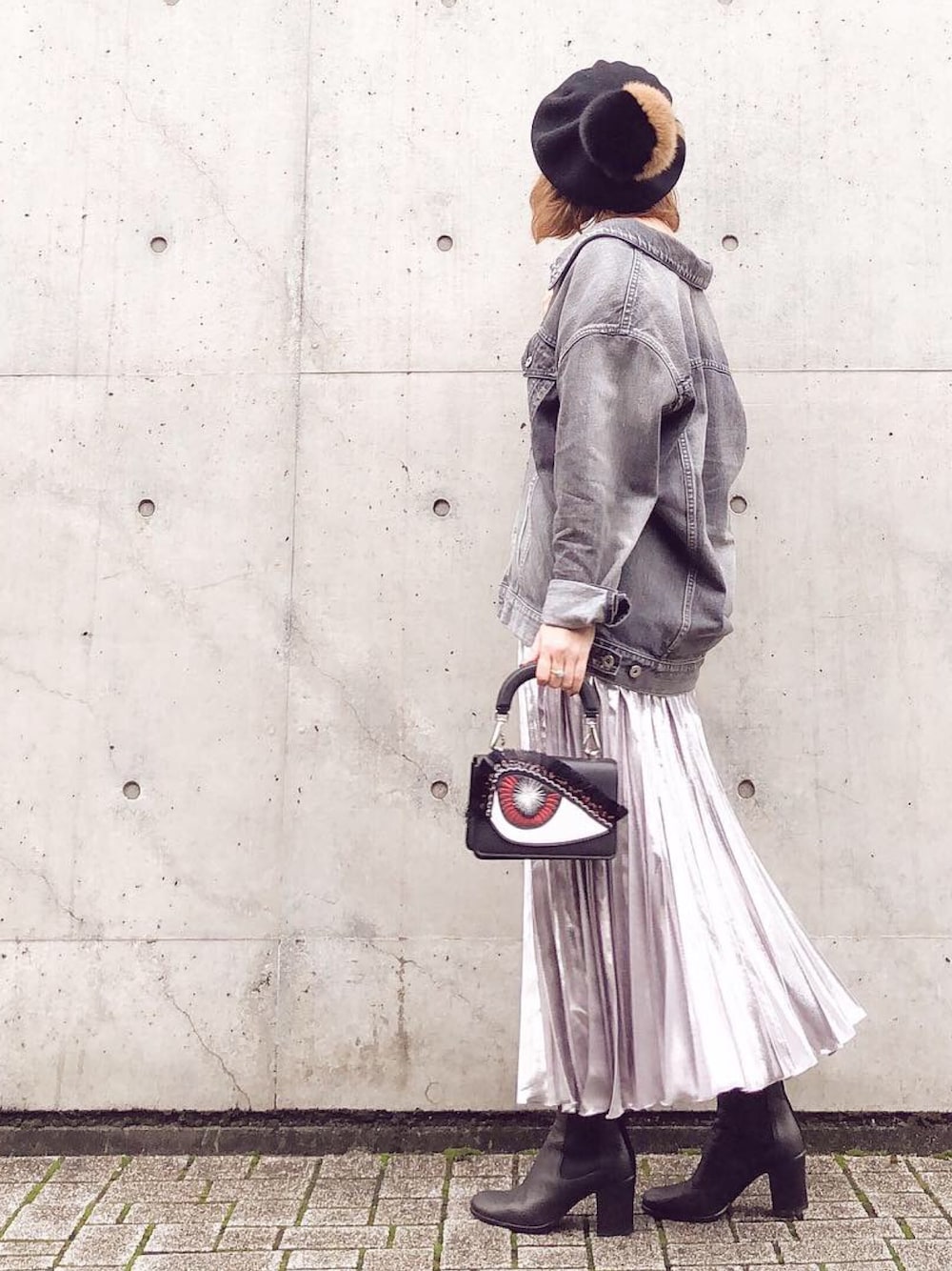 グレー系のデニムジャケット、ブラック系のハンドバッグ、シルバー系のスカートを着用したレディースの秋コーディネートの1枚目の写真