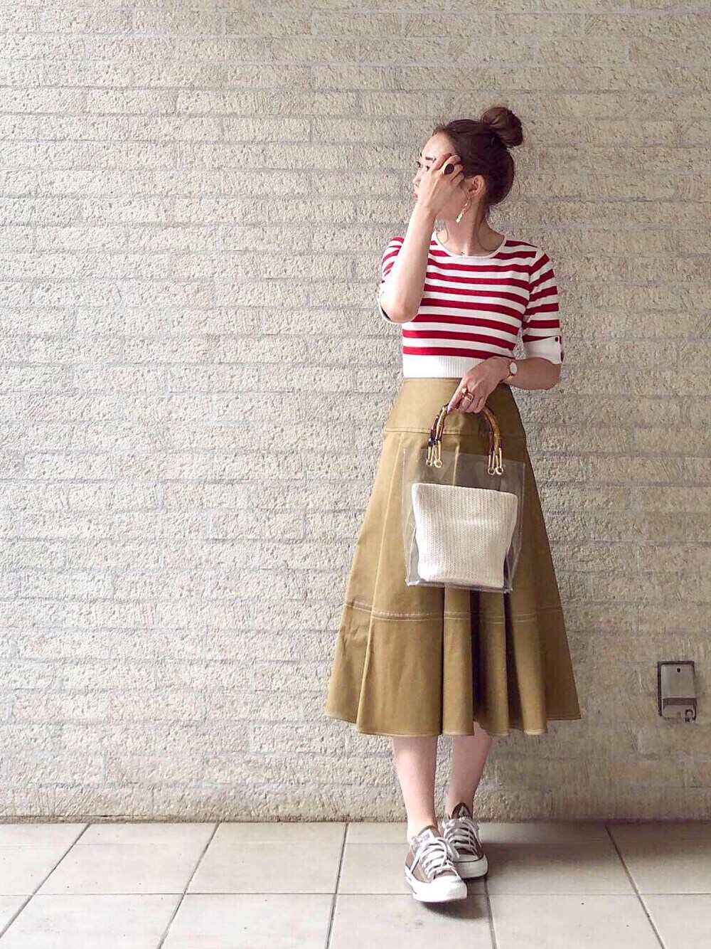 ベージュ系のスカート、レッド系のニット/セーター、ホワイト系のバッグを着用したレディースの春コーディネートの1枚目の写真
