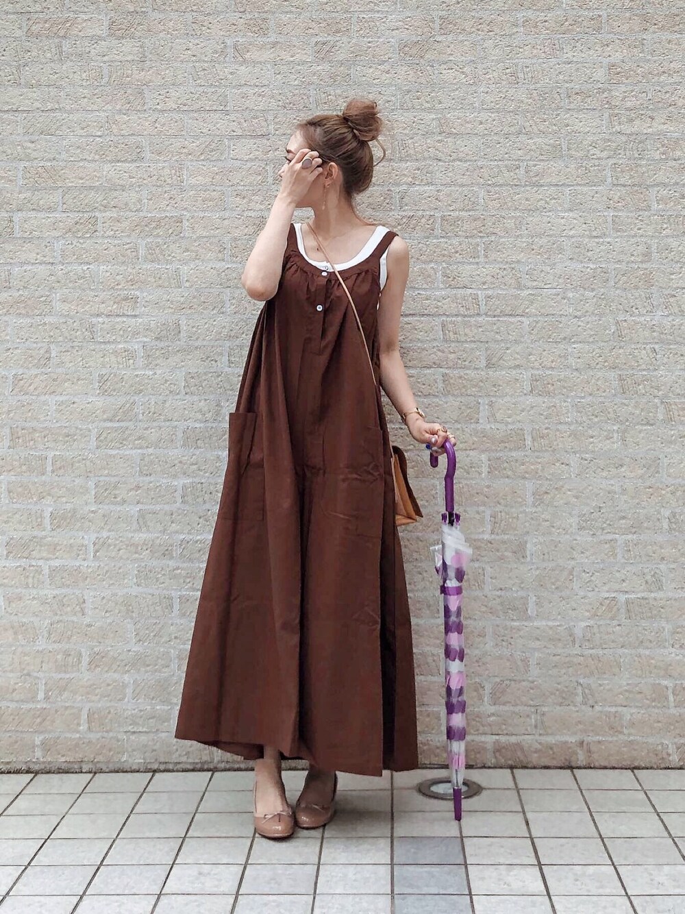 ブラウン系のサロペット/オーバーオール、ベージュ系のハンドバッグ、ベージュ系のレインシューズを着用したレディースの春コーディネートの1枚目の写真