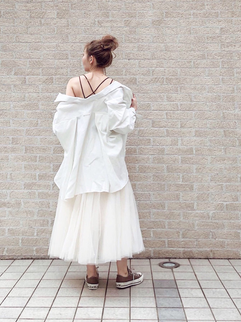 ホワイト系のミリタリージャケット、ホワイト系のスカート、ブラウン系のキャミソールを着用したレディースの春コーディネートの1枚目の写真