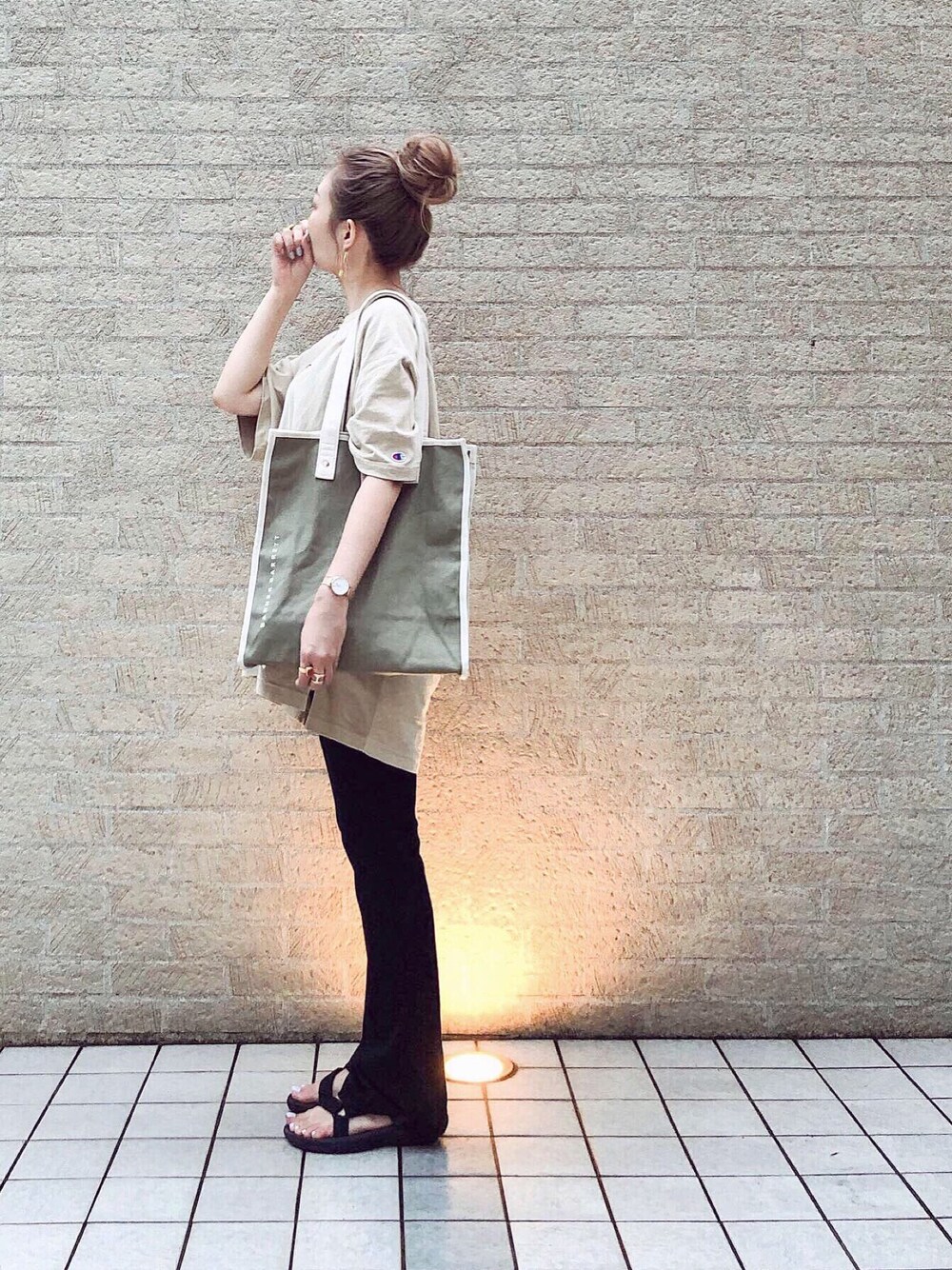 グリーン系のトートバッグ、ベージュ系のTシャツ/カットソー、ブラック系のパンツを着用したレディースの夏コーディネートの1枚目の写真