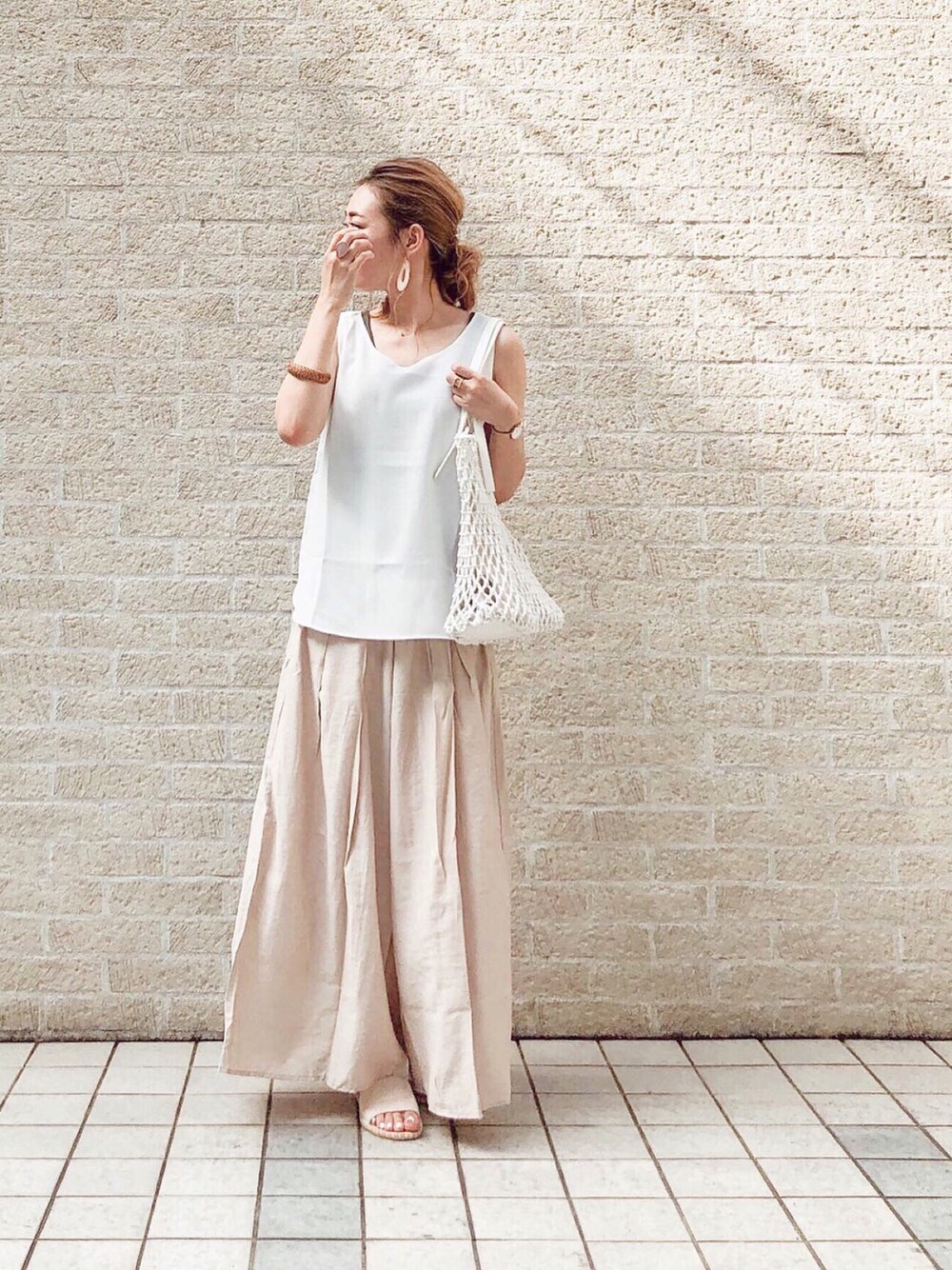 ホワイト系のタンクトップ、ベージュ系のパンツ、ホワイト系のトートバッグを着用したレディースの夏コーディネートの1枚目の写真