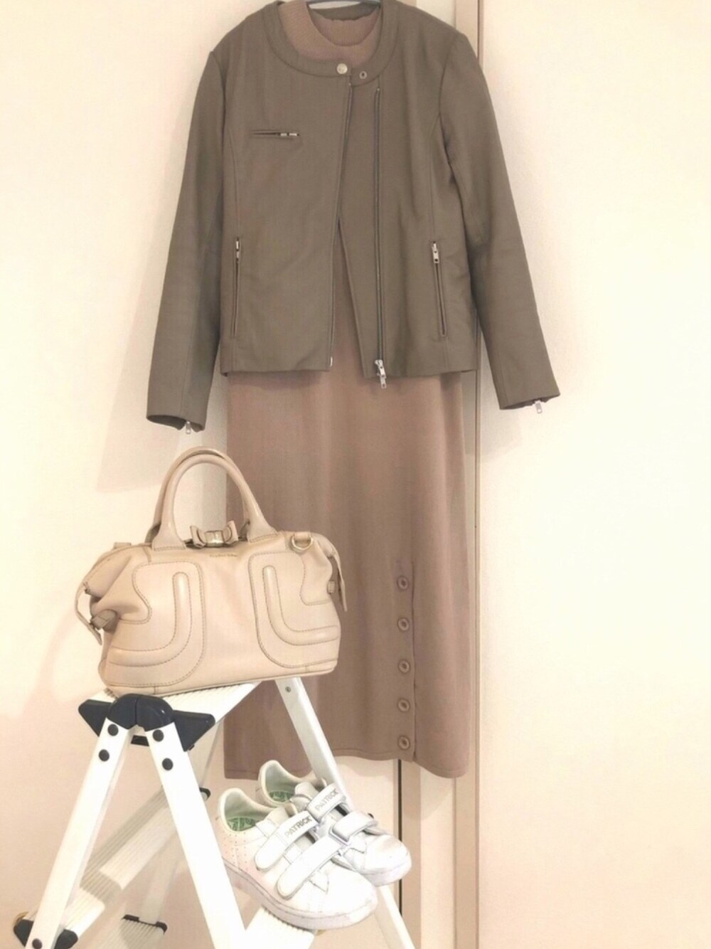 ベージュ系のワンピース、ベージュ系のショルダーバッグ、グレー系のライダースジャケットを着用したレディースの春コーディネートの1枚目の写真