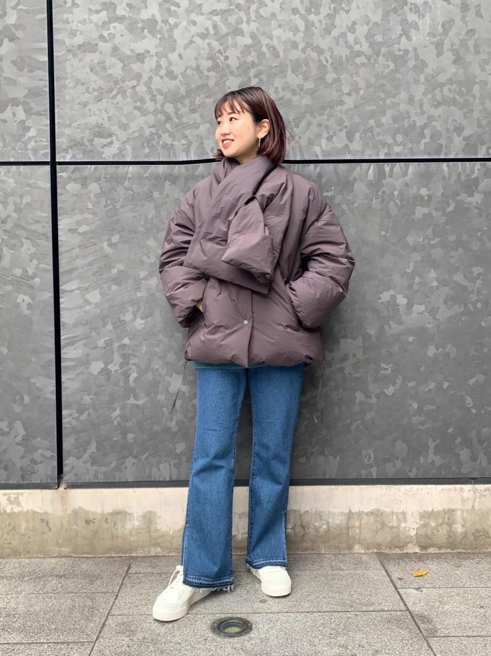 グリーン系のニット/セーター、ブルー系のデニムパンツ、ホワイト系のスニーカーを着用したレディースの秋コーディネートの1枚目の写真