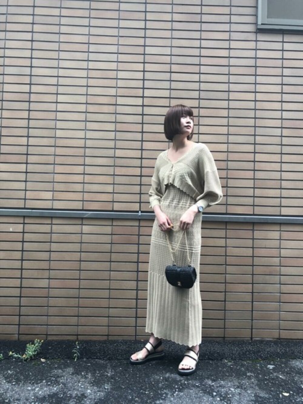 ベージュ系のカーディガン/ボレロ、ベージュ系のワンピース、ゴールド系のサンダルを着用したレディースの春コーディネートの1枚目の写真