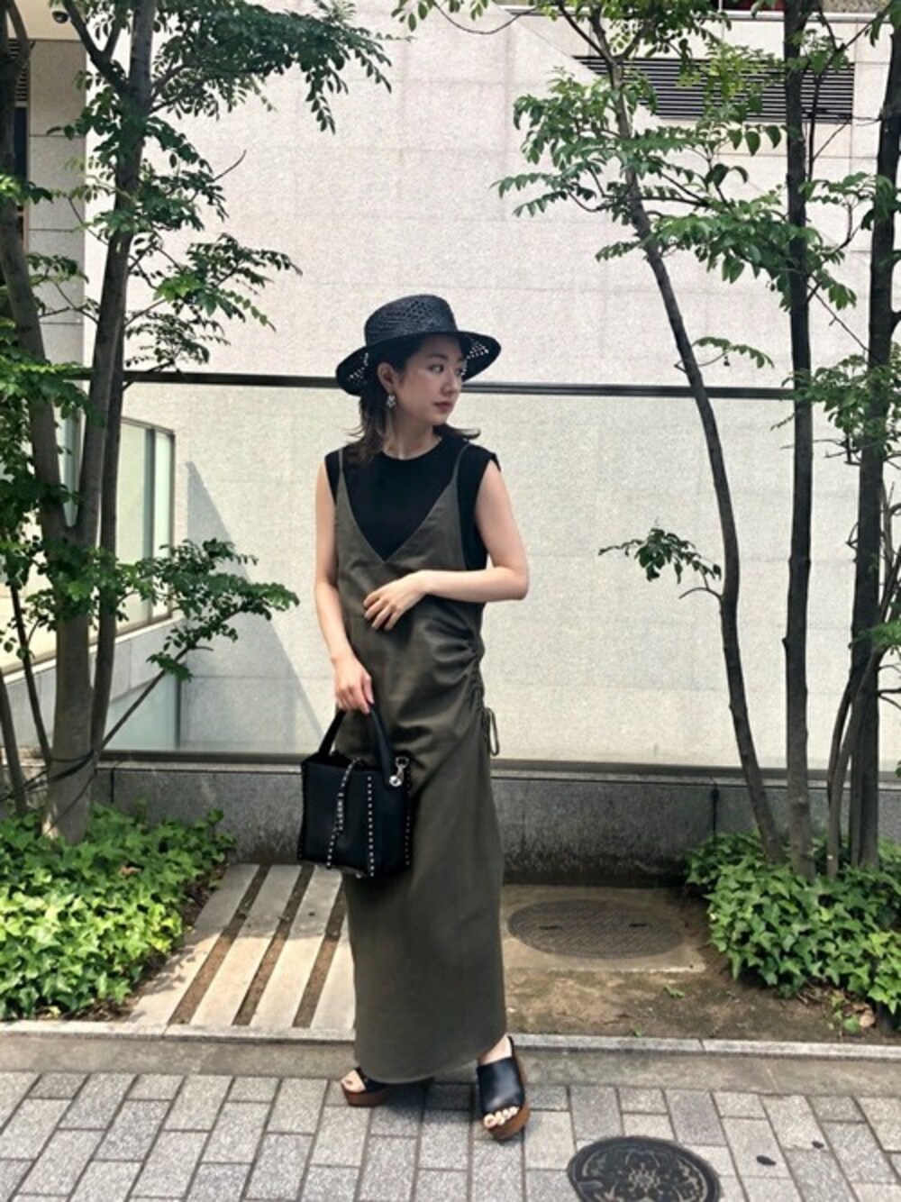 グリーン系のワンピース、ブラック系のショルダーバッグ、ブラック系のサンダルを着用したレディースの夏コーディネートの1枚目の写真