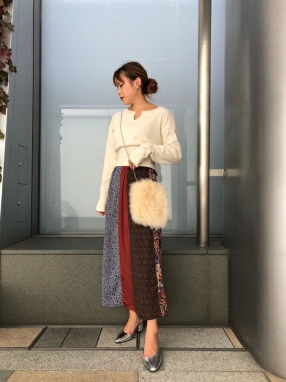 ブラウン系のスカート、ベージュ系のTシャツ/カットソー、シルバー系のパンプスを着用したレディースの秋コーディネートの1枚目の写真