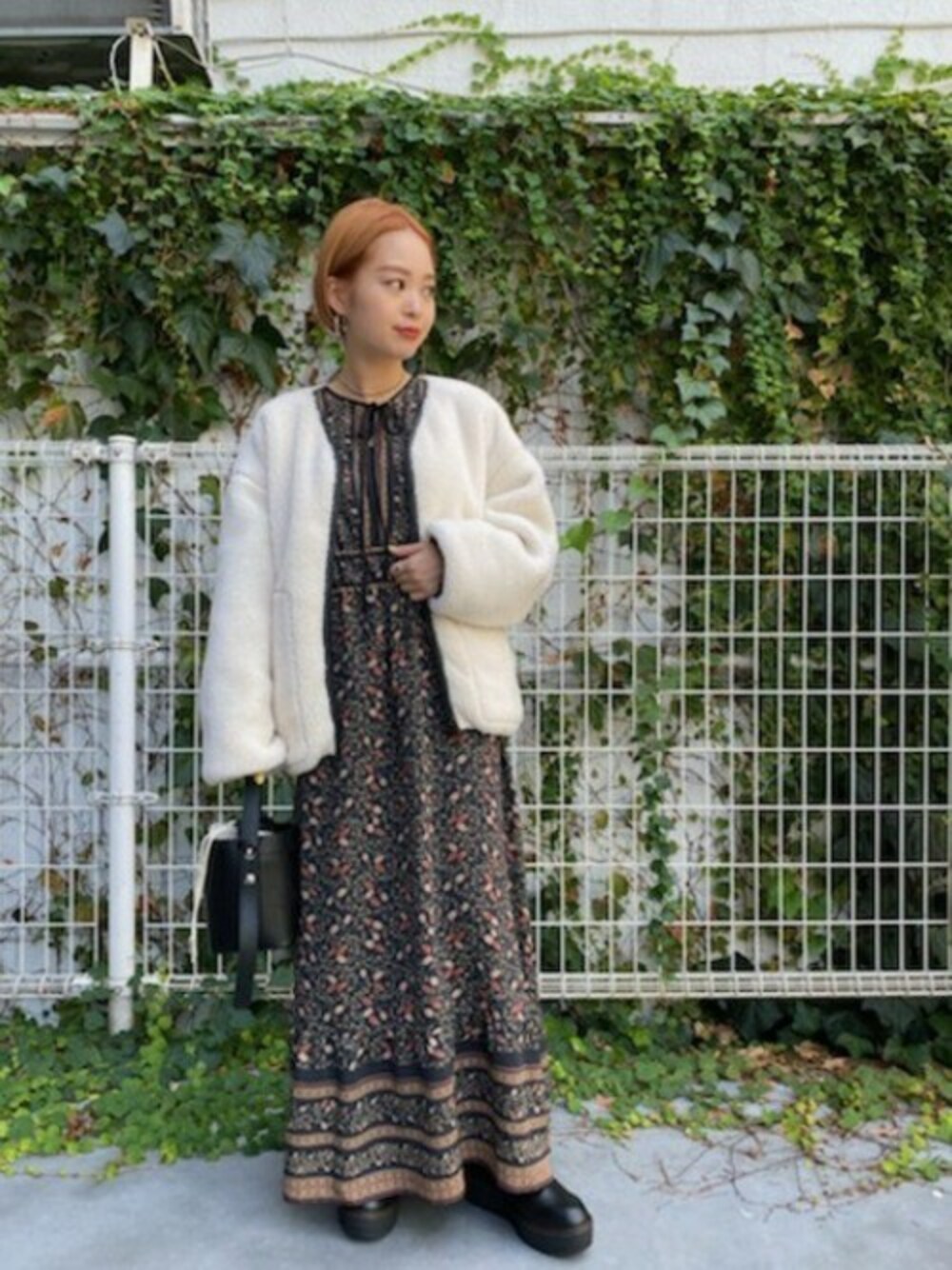 ブラック系のワンピース、ホワイト系のブルゾン、ブラック系のショルダーバッグを着用したレディースの秋コーディネートの1枚目の写真