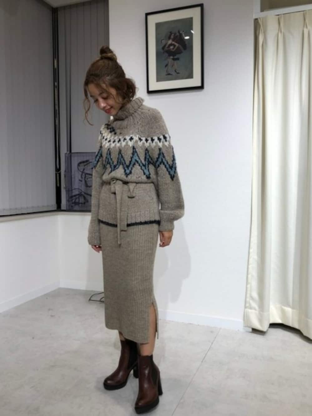 ベージュ系のニット/セーター、ベージュ系のスカート、ブラウン系のブーツを着用したレディースの秋コーディネートの1枚目の写真