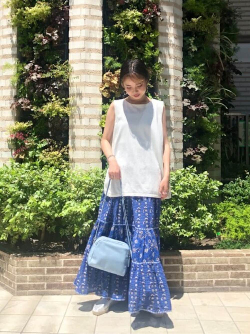 ホワイト系のニット/セーター、ブルー系のスカート、ブルー系のショルダーバッグを着用したレディースの夏コーディネートの1枚目の写真