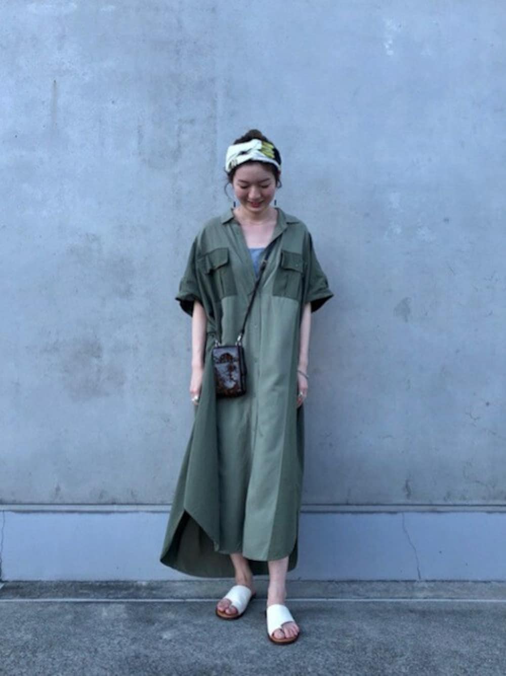 グリーン系のシャツワンピース、ホワイト系のサンダル、ブラウン系の財布を着用したレディースの秋コーディネートの1枚目の写真