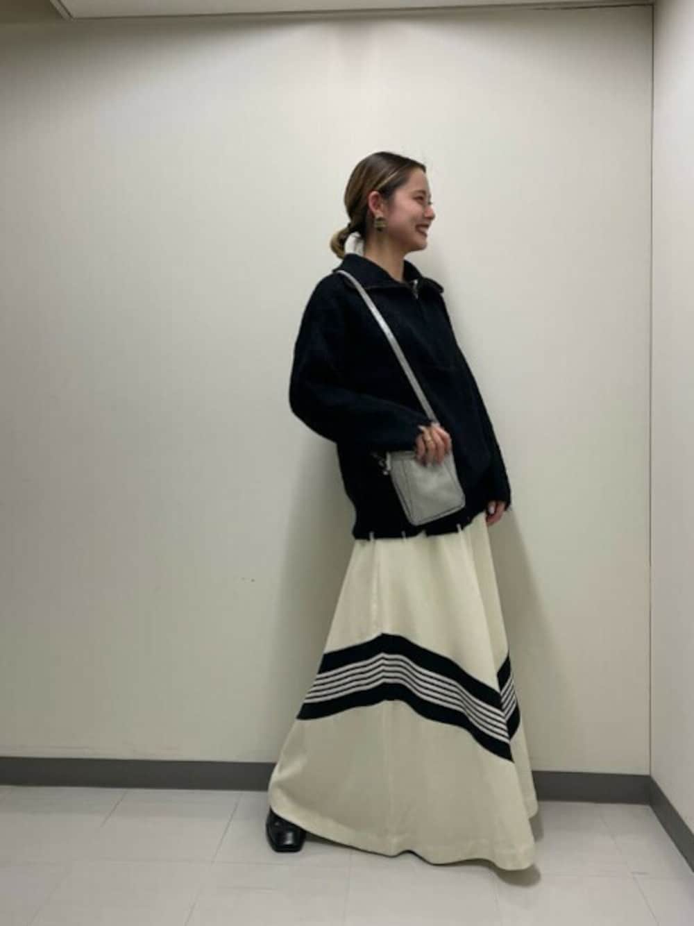 ブラック系のニット/セーター、シルバー系のショルダーバッグ、ホワイト系のスカートを着用したレディースの冬コーディネートの1枚目の写真