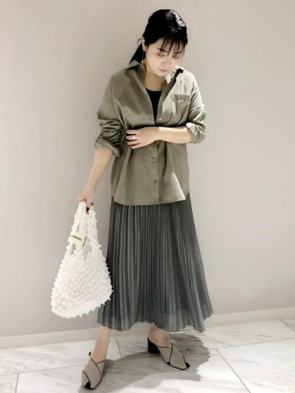 グリーン系のシャツ/ブラウス、グレー系のタンクトップ、グレー系のスカートを着用したレディースの春コーディネートの1枚目の写真