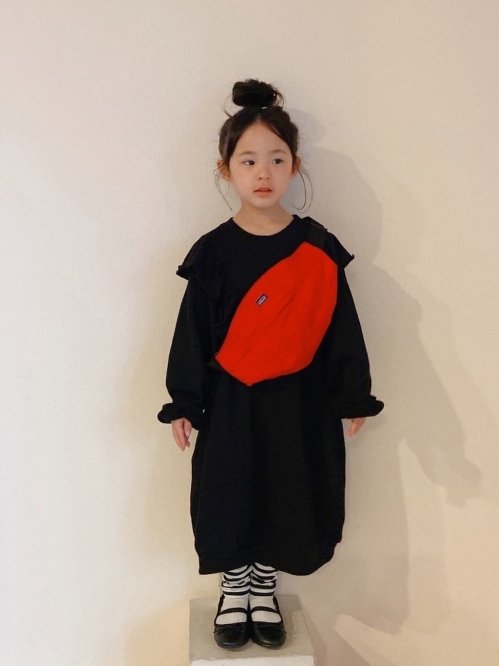 ブラック系のワンピース、レッド系のボディバッグ/ウエストポーチ、ブラック系のバレエシューズを着用したキッズの春コーディネートの1枚目の写真