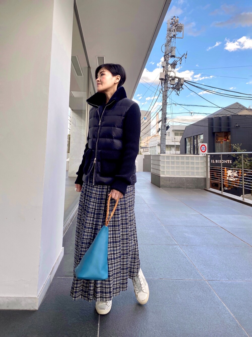 ブルー系のダウンジャケット/コート、グレー系のスカート、ブルー系のハンドバッグを着用したレディースの秋コーディネートの1枚目の写真