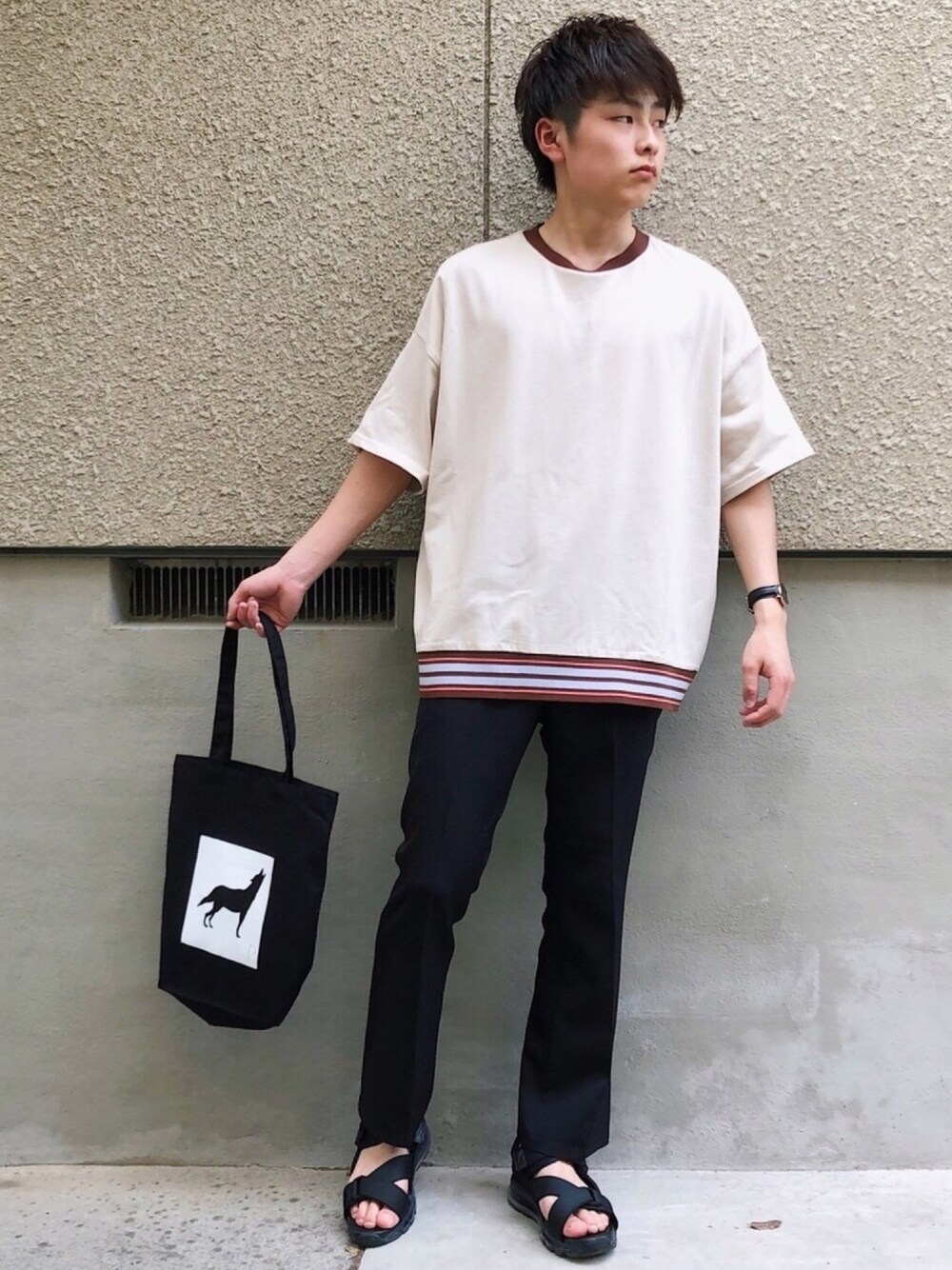 ベージュ系のTシャツ/カットソー、ブラック系のスラックス、ブラック系のサンダルを着用したメンズの春コーディネートの1枚目の写真