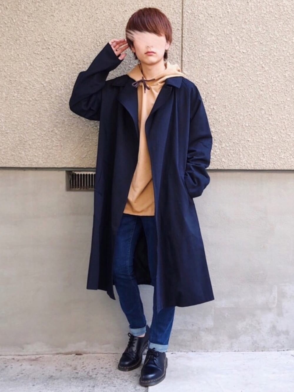 ブラック系のトレンチコート、ベージュ系のTシャツ/カットソー、ブルー系のパンツを着用したメンズの秋コーディネートの1枚目の写真