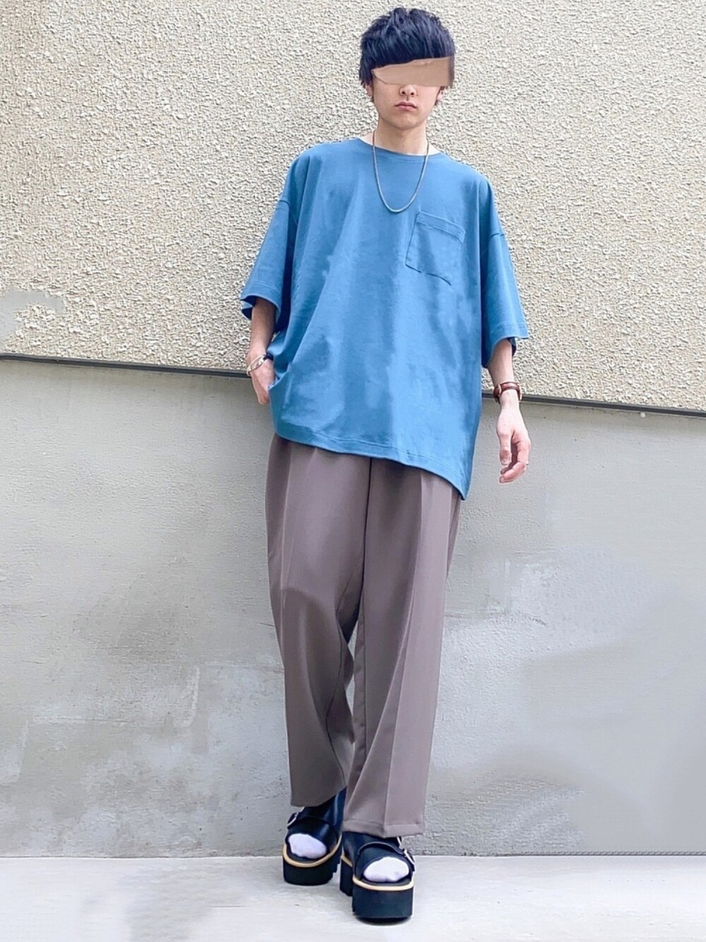 ブルー系のTシャツ/カットソー、ブラウン系のスラックス、ブラック系のサンダルを着用したメンズの夏コーディネートの1枚目の写真