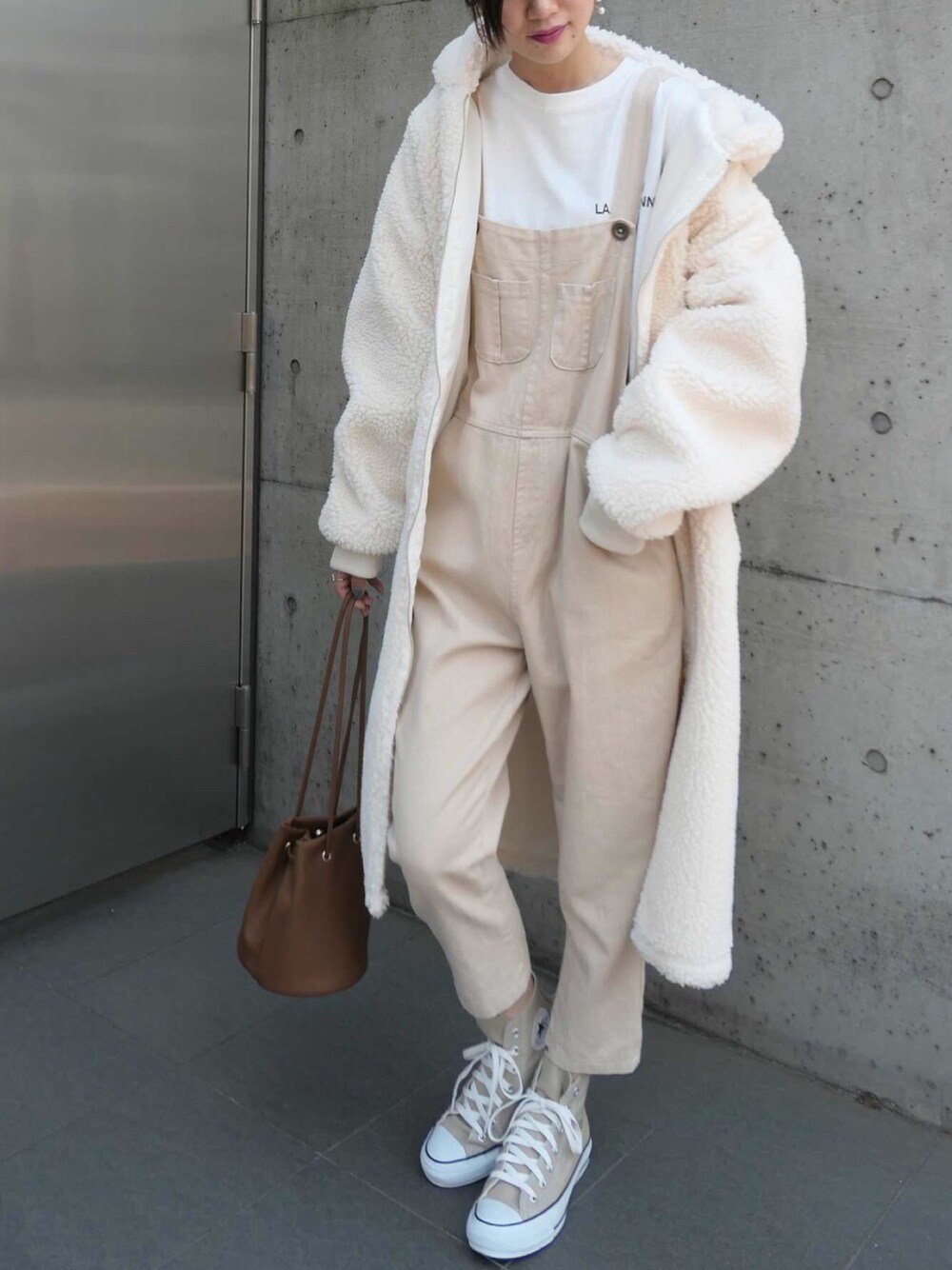 ベージュ系のスニーカー、ブラウン系のハンドバッグ、ベージュ系のサロペット/オーバーオールを着用したレディースの秋コーディネートの1枚目の写真