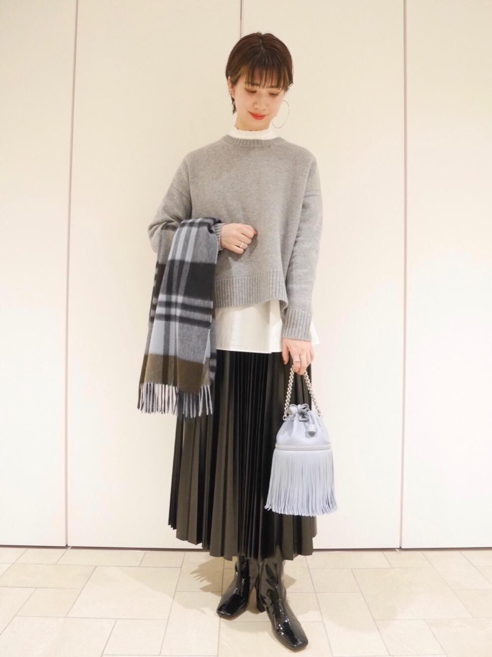 ブラック系のスカート、ホワイト系のシャツ/ブラウス、グレー系のニット/セーターを着用したレディースの冬コーディネートの1枚目の写真