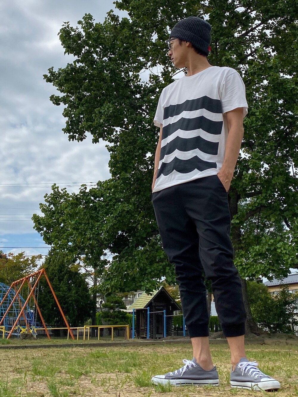 グレー系のスニーカー、その他のTシャツ/カットソー、ブラック系のニットキャップ/ビーニーを着用したメンズの秋コーディネートの1枚目の写真