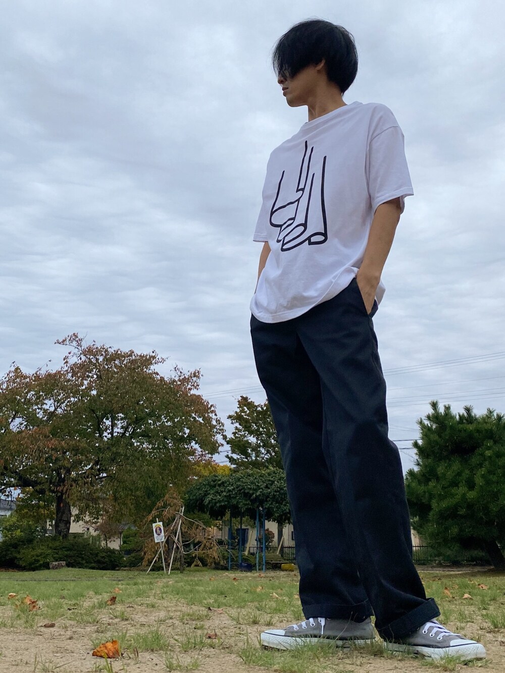 グレー系のスニーカー、ブラック系のチノパンツ、その他のTシャツ/カットソーを着用したメンズの秋コーディネートの1枚目の写真