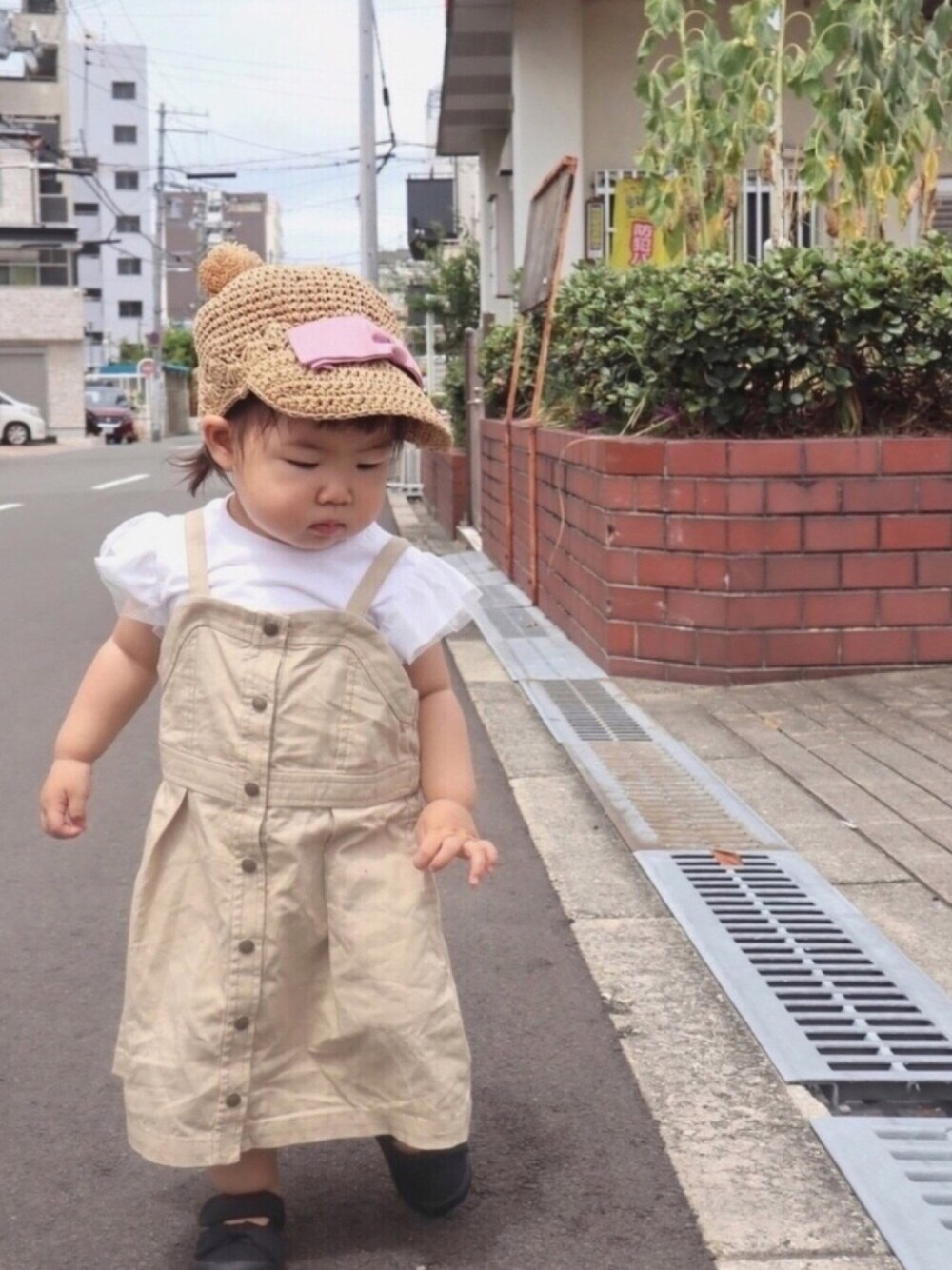 ホワイト系のTシャツ/カットソー、ベージュ系のジャンパースカート、ブラック系のバレエシューズを着用したキッズの夏コーディネートの1枚目の写真