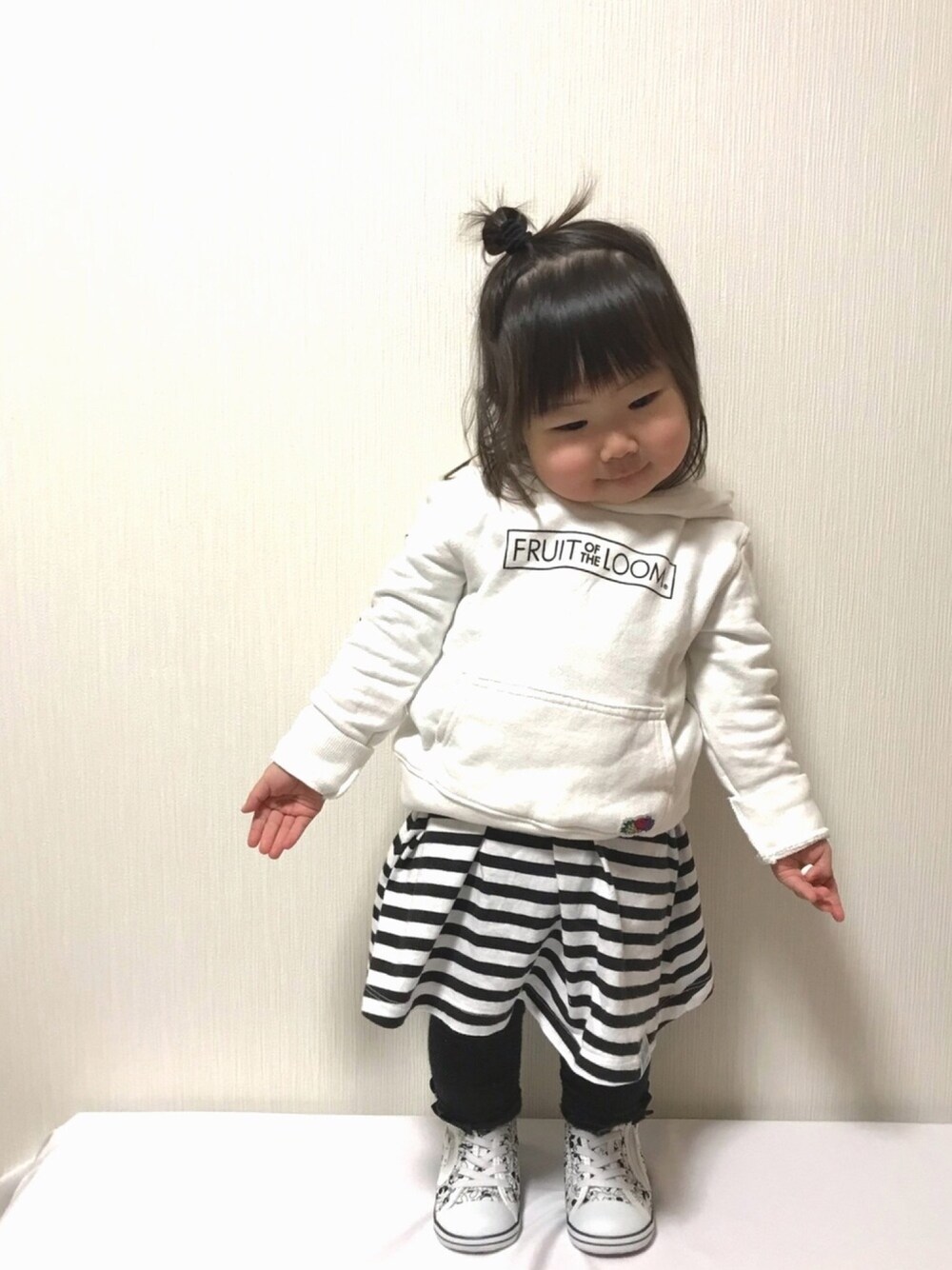 ホワイト系のトップス、ブラック系のワンピース、ホワイト系のスニーカーを着用したキッズの冬コーディネートの1枚目の写真