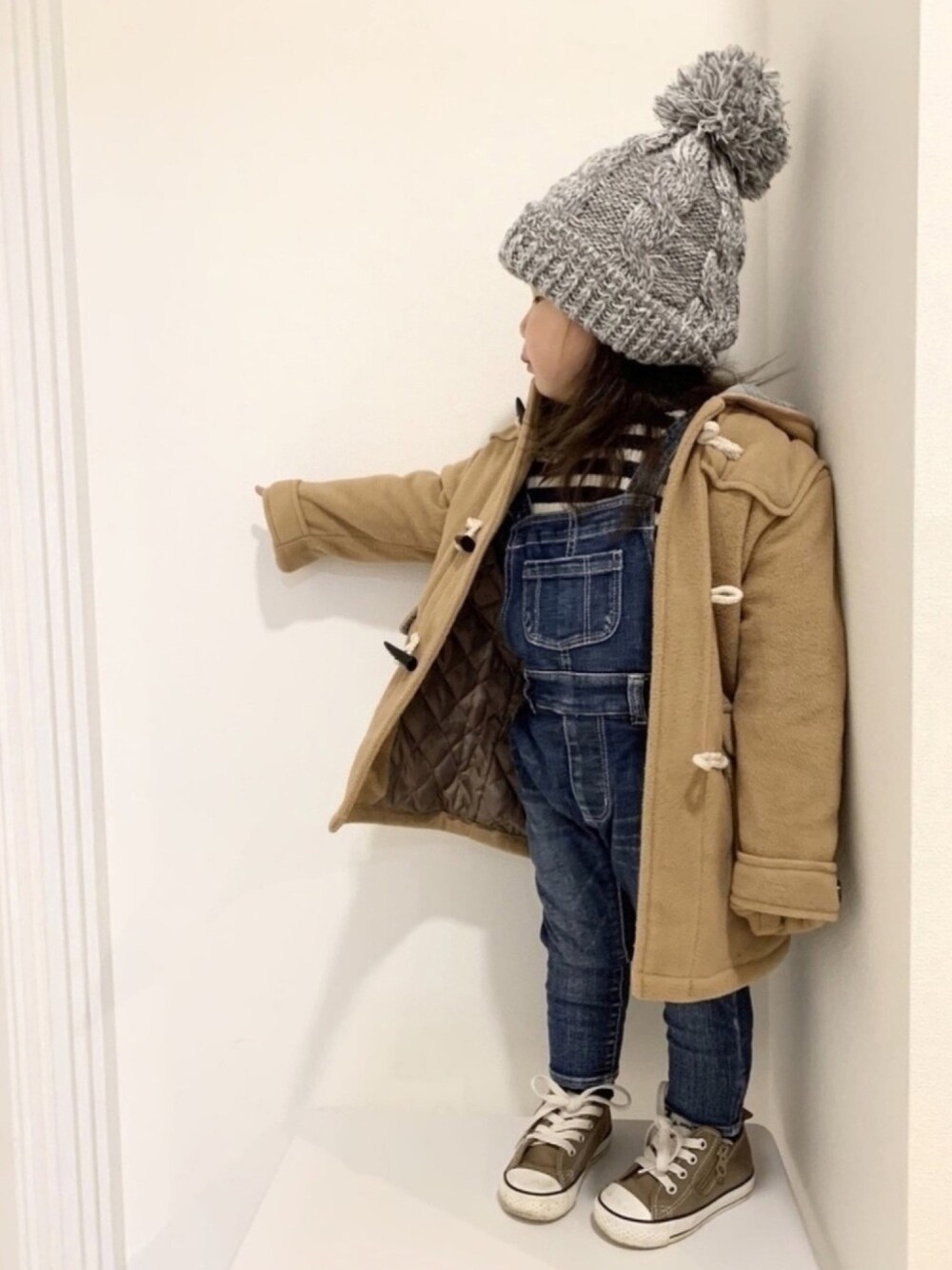 ブルー系のニット/セーター、ブルー系のサロペット/オーバーオール、ブラウン系のダッフルコートを着用したキッズの冬コーディネートの1枚目の写真