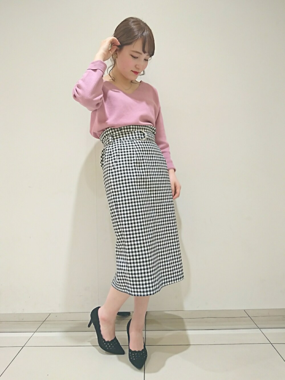 ブラック系のスカート、ピンク系のニット/セーター、ブラック系のパンプスを着用したレディースの冬コーディネートの1枚目の写真