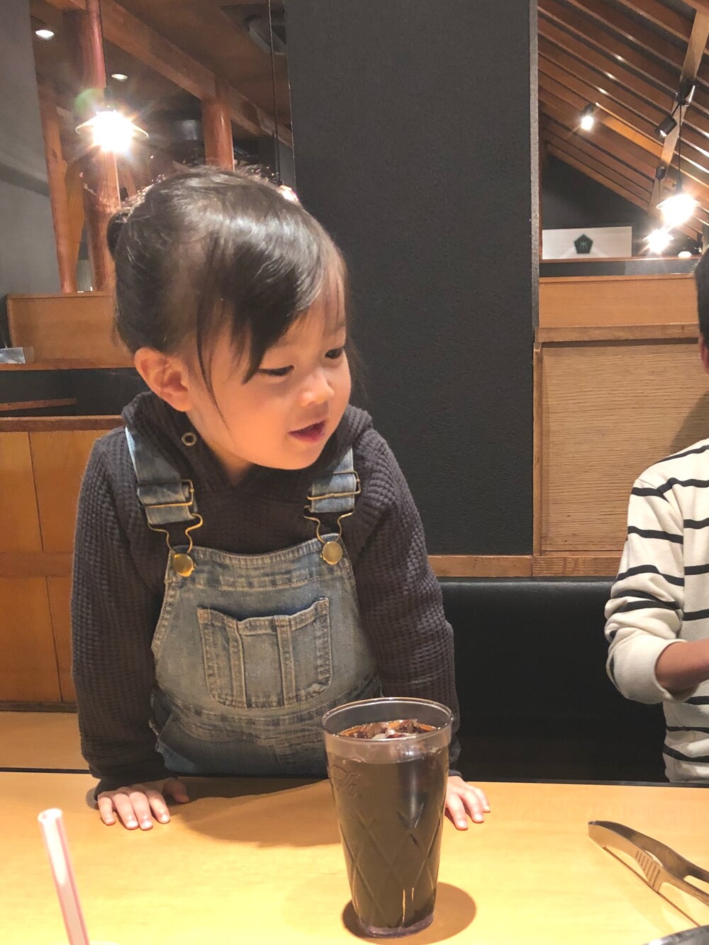 グレー系のパーカー、ブルー系のサロペット/オーバーオール、ブラック系のスニーカーを着用したキッズの冬コーディネートの1枚目の写真