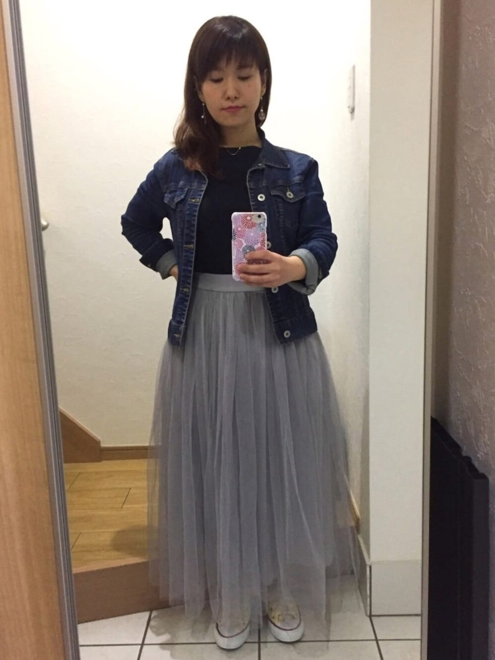 グレー系のスカート、ブルー系のデニムジャケット、ホワイト系のスニーカーを着用したレディースの春コーディネートの1枚目の写真