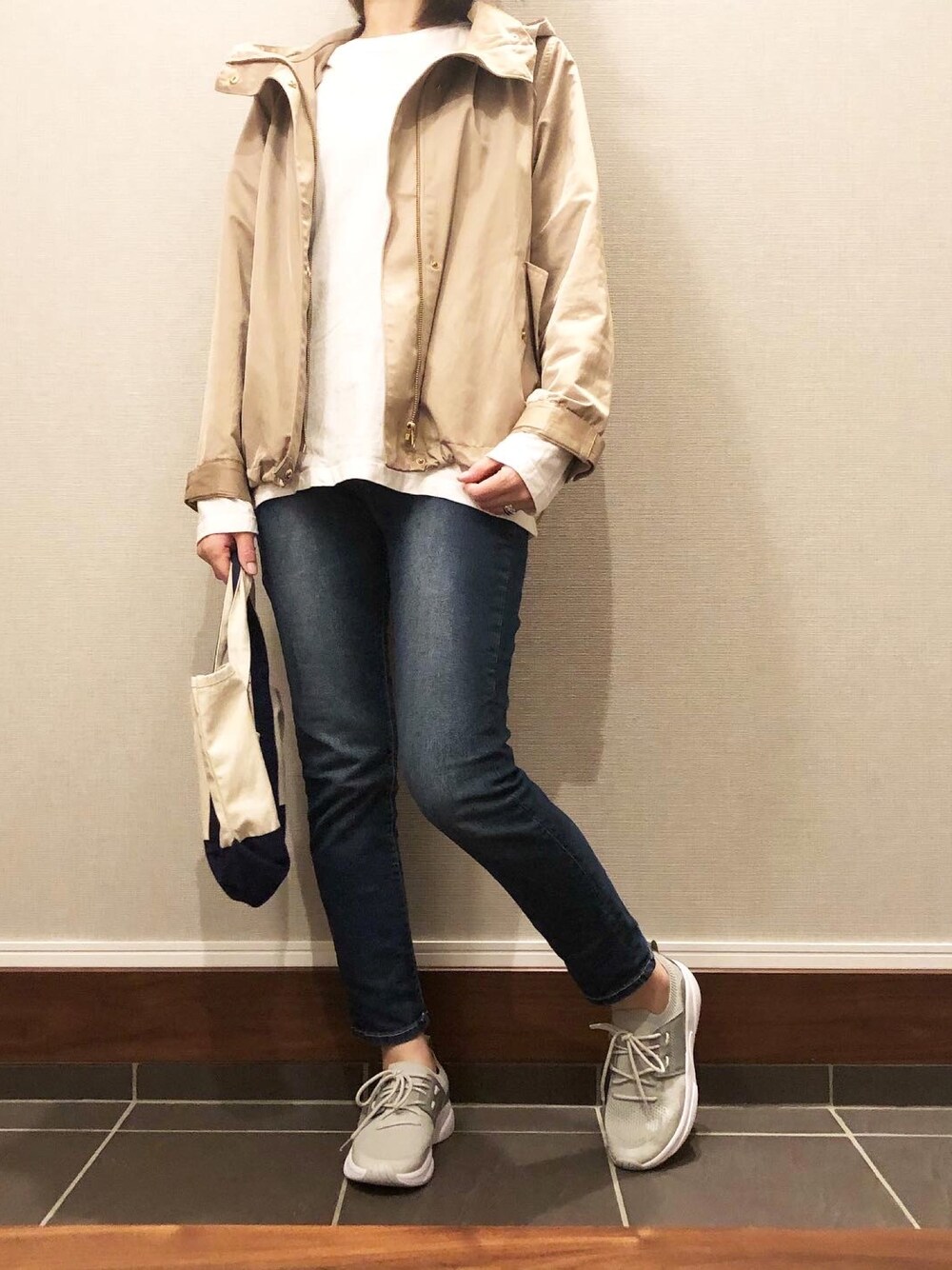 ベージュ系のマウンテンパーカー、グレー系のスニーカーを着用したレディースの春コーディネートの1枚目の写真