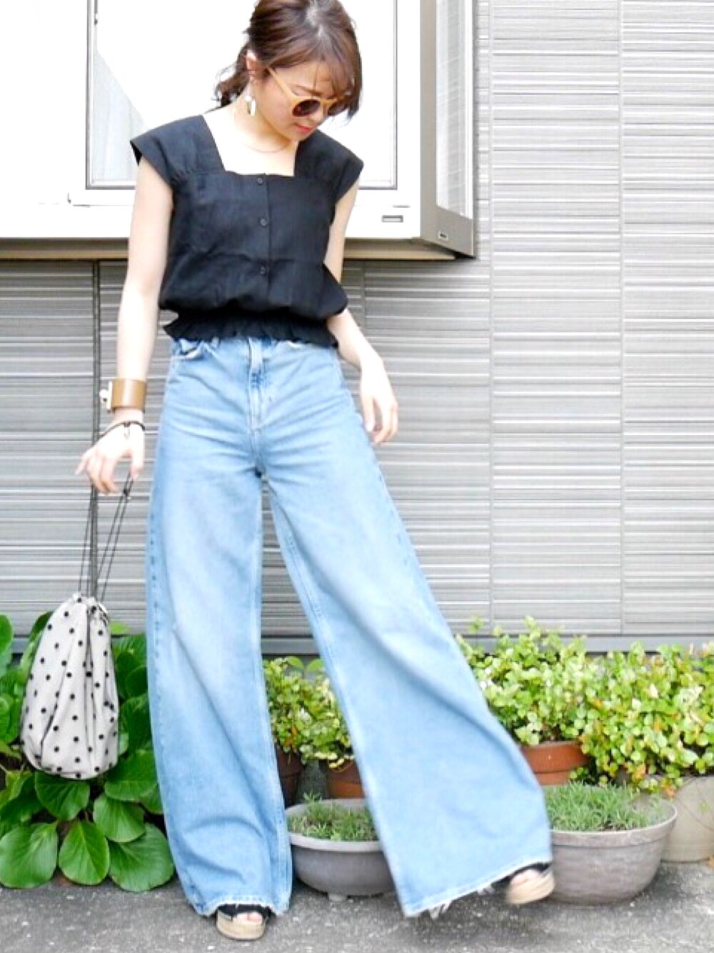 グレー系のバッグ、ブルー系のデニムパンツ、ブラック系のサンダルを着用したレディースの春コーディネートの1枚目の写真