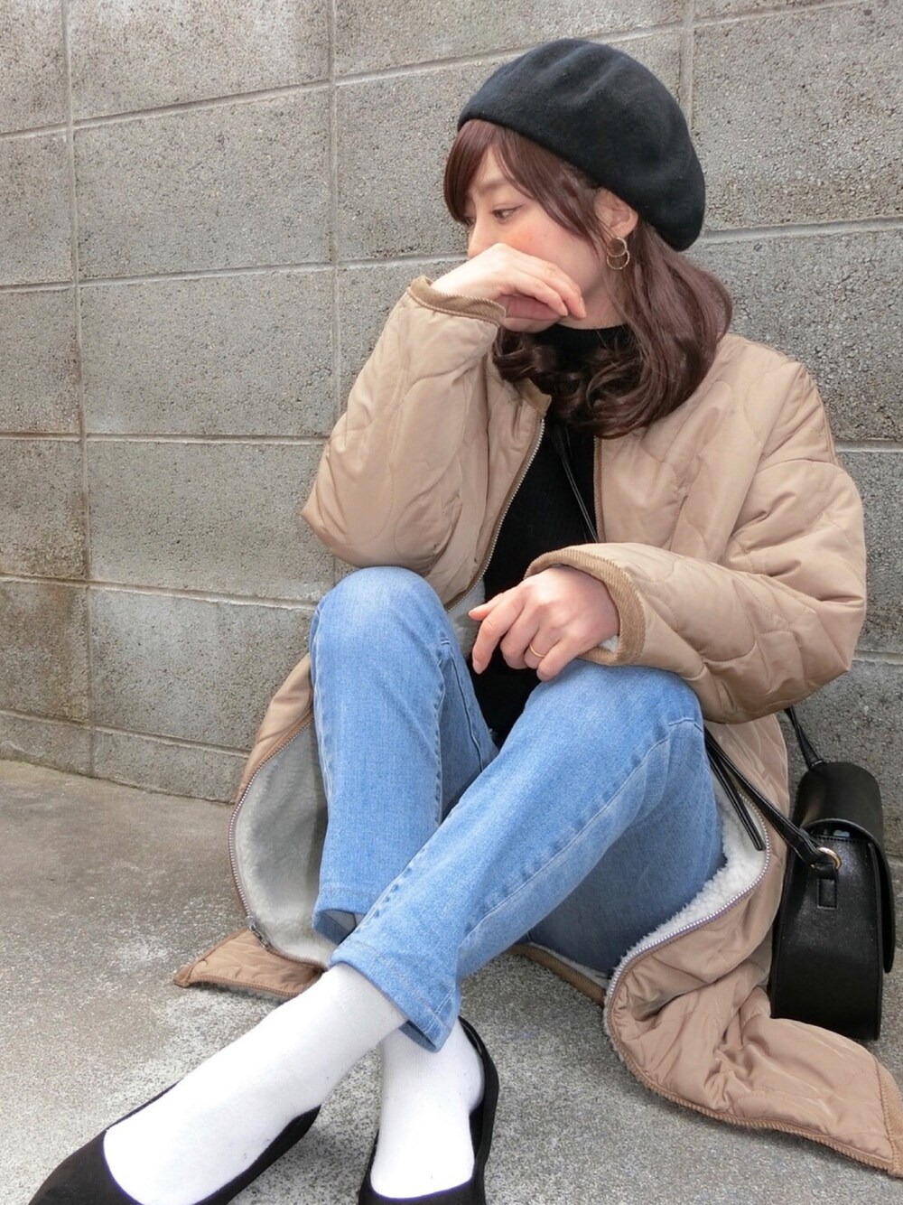 ブラック系のニット/セーター、ベージュ系のその他アウター、ブルー系のデニムパンツを着用したレディースの冬コーディネートの1枚目の写真