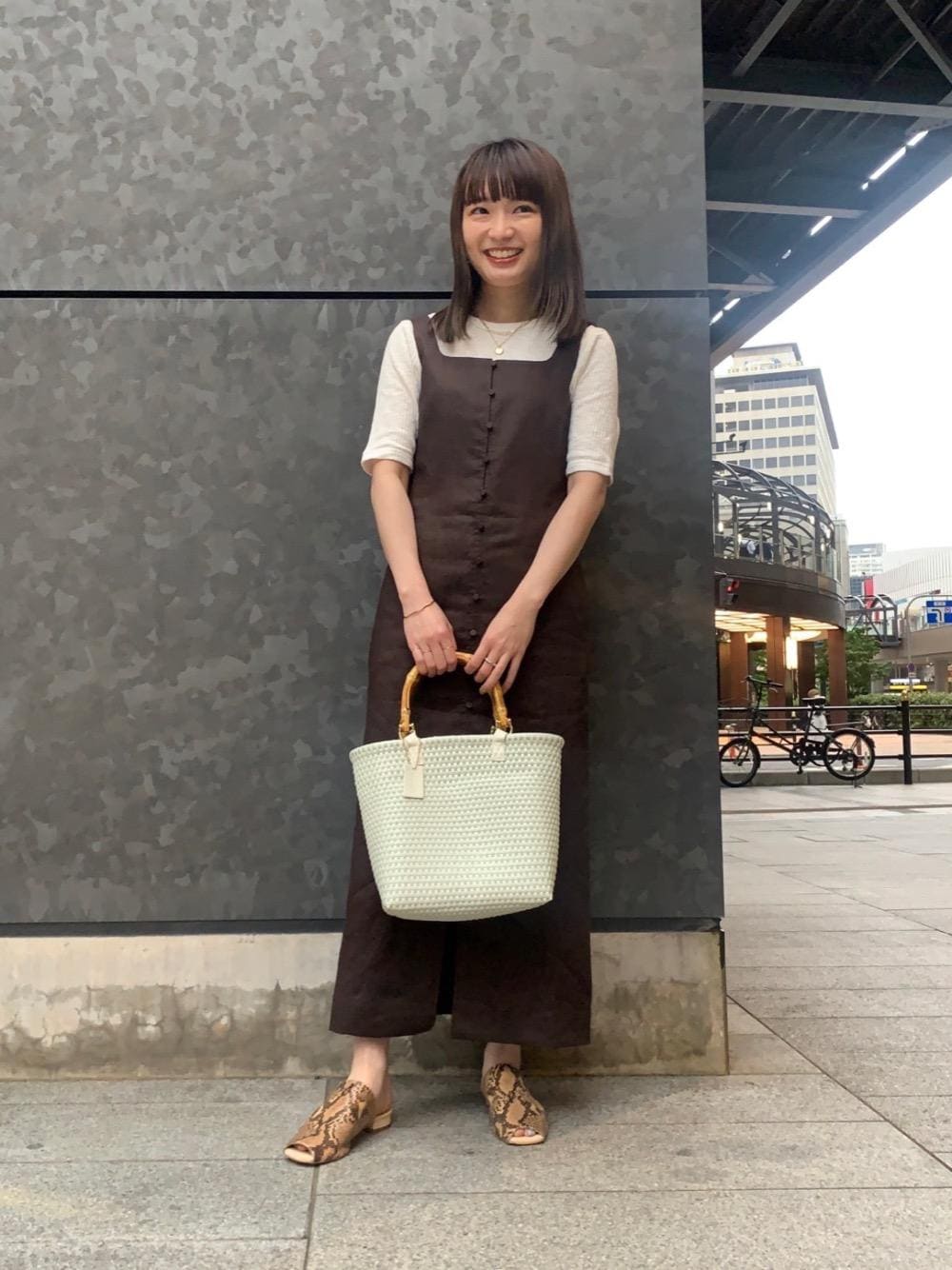 ホワイト系のかごバッグ、ホワイト系のTシャツ/カットソー、ブラウン系のワンピースを着用したレディースの春コーディネートの1枚目の写真