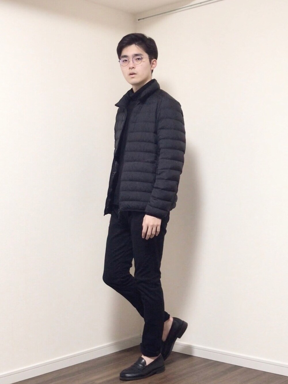 ブラック系のダウンジャケット/コート、ブラック系のTシャツ/カットソー、ブラック系のデニムパンツを着用したメンズの春コーディネートの1枚目の写真