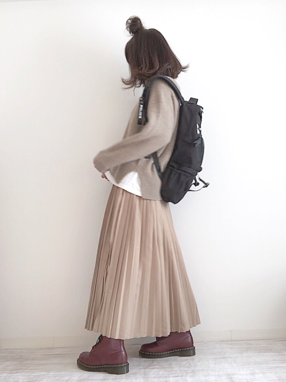 グレー系のニット/セーター、ホワイト系のTシャツ/カットソー、ベージュ系のスカートを着用したレディースの秋コーディネートの1枚目の写真