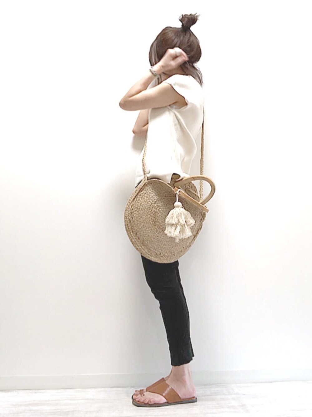 ホワイト系のニット/セーター、ブラック系のデニムパンツ、ベージュ系のバッグを着用したレディースの春コーディネートの1枚目の写真