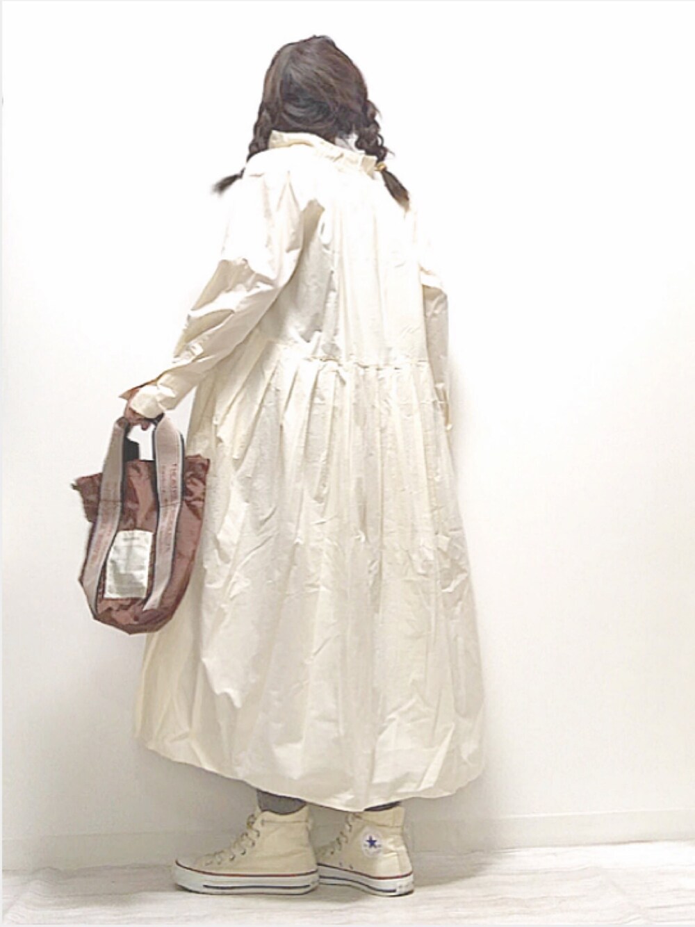 ホワイト系のワンピース、ブラウン系のハンドバッグ、グレー系のパンツを着用したレディースの秋コーディネートの1枚目の写真