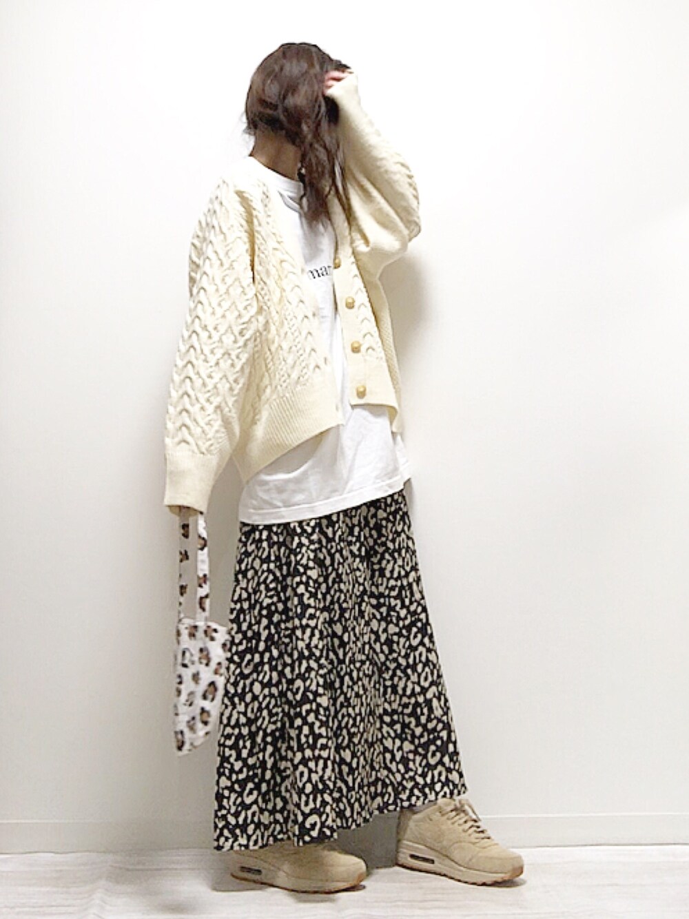 ホワイト系のカーディガン/ボレロ、ブラック系のスカート、ベージュ系のスニーカーを着用したレディースの冬コーディネートの1枚目の写真