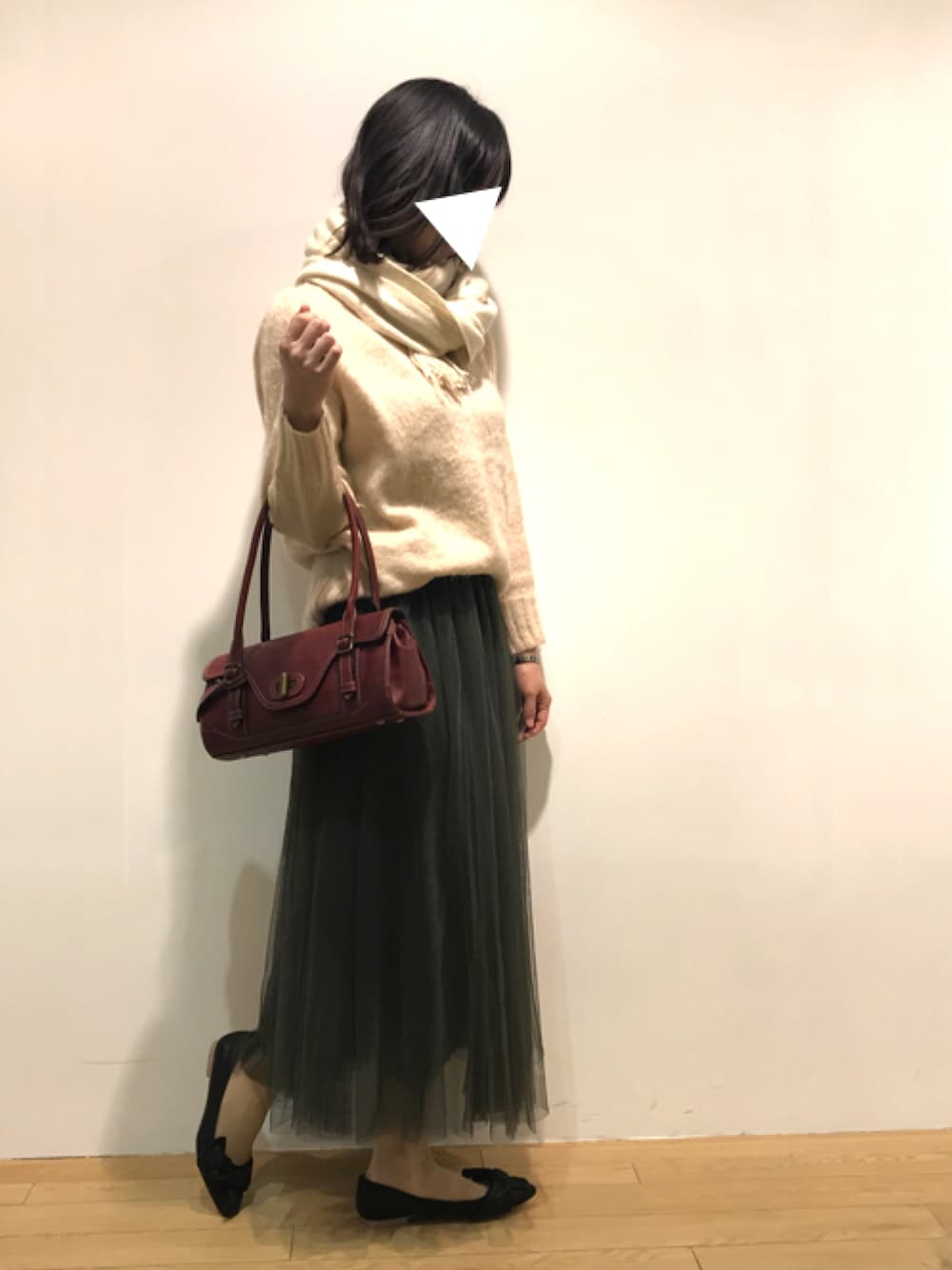 ブラック系のパンプス、グリーン系のスカート、ベージュ系のマフラーを着用したレディースの春コーディネートの1枚目の写真