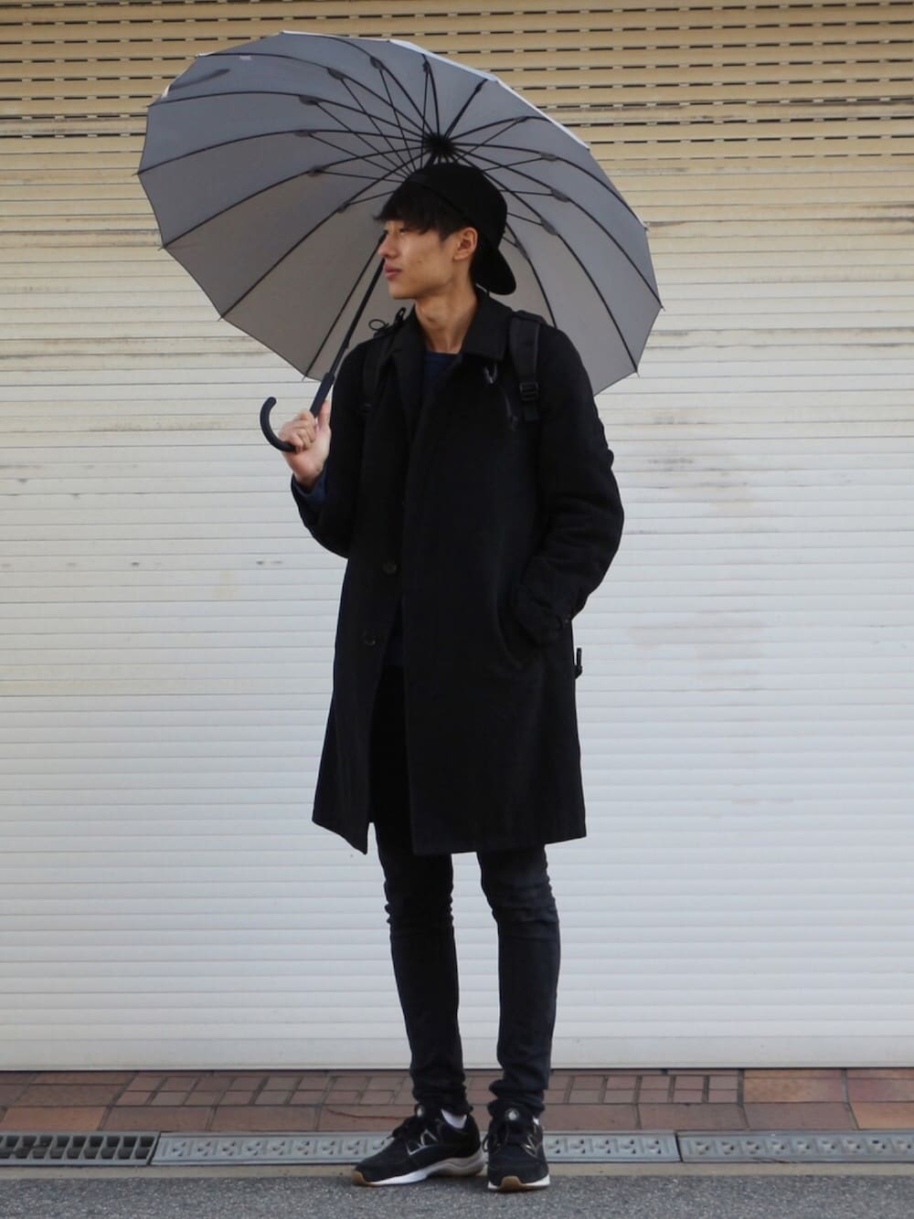 ブラック系のテーラードジャケット、ブラック系のデニムパンツ、ブルー系のスニーカーを着用したメンズの冬コーディネートの1枚目の写真