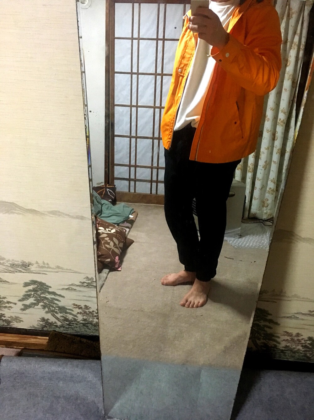 ブラック系のその他パンツ、オレンジ系のマウンテンパーカー、ホワイト系のスウェットを着用したメンズの冬コーディネートの1枚目の写真