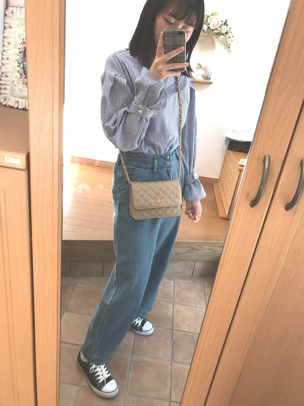 ブルー系のトップス、ベージュ系のショルダーバッグ、ブルー系のデニムパンツを着用したレディースの夏コーディネートの1枚目の写真