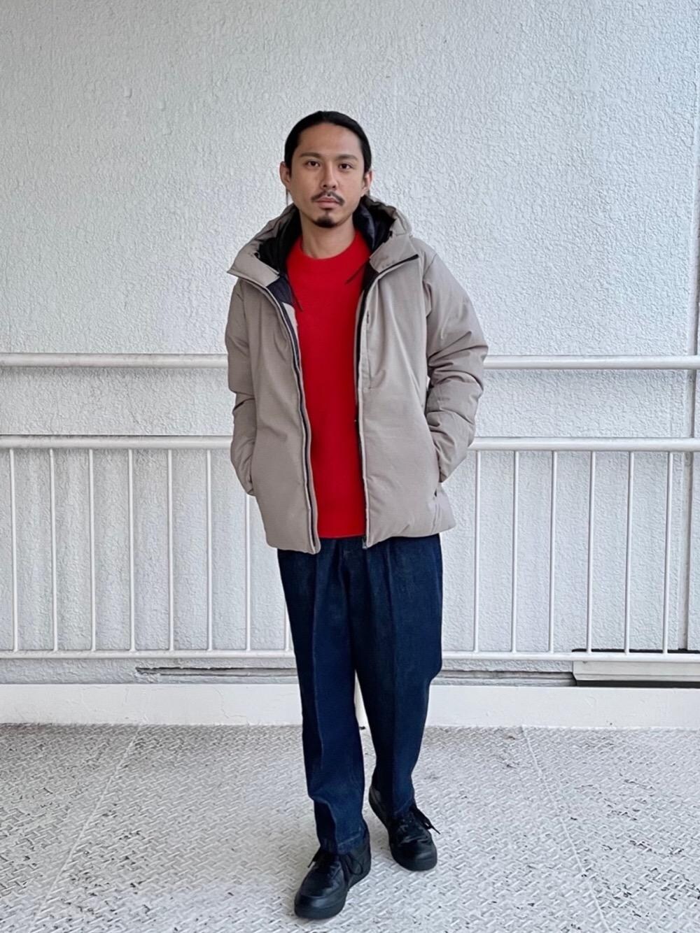 ブラック系のスニーカー、ブルー系のデニムパンツ、オレンジ系のニット/セーターを着用したメンズの秋コーディネートの1枚目の写真