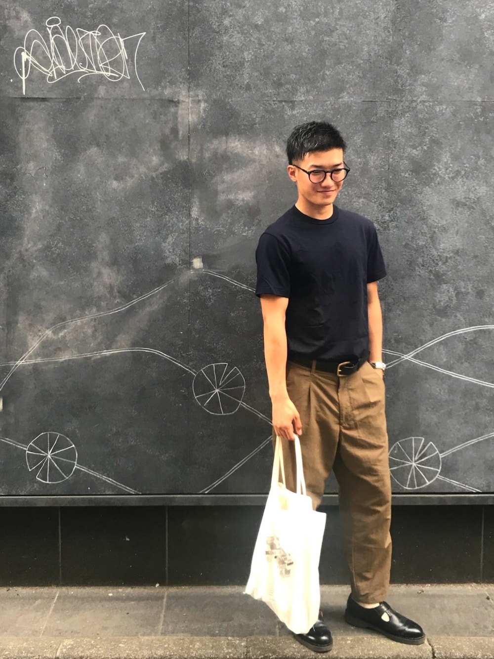 「革靴、Tシャツ、タックイン、サングラス、壁にラクガキ、おしゃれさんと繋がりたい、トートバッグ、逆光で見えない」｜「BuddyOpticalのアイテム（サングラス、ブラック系）」を使った、takaさん（メンズ・171cm）の夏コーディネートの1枚目の写真