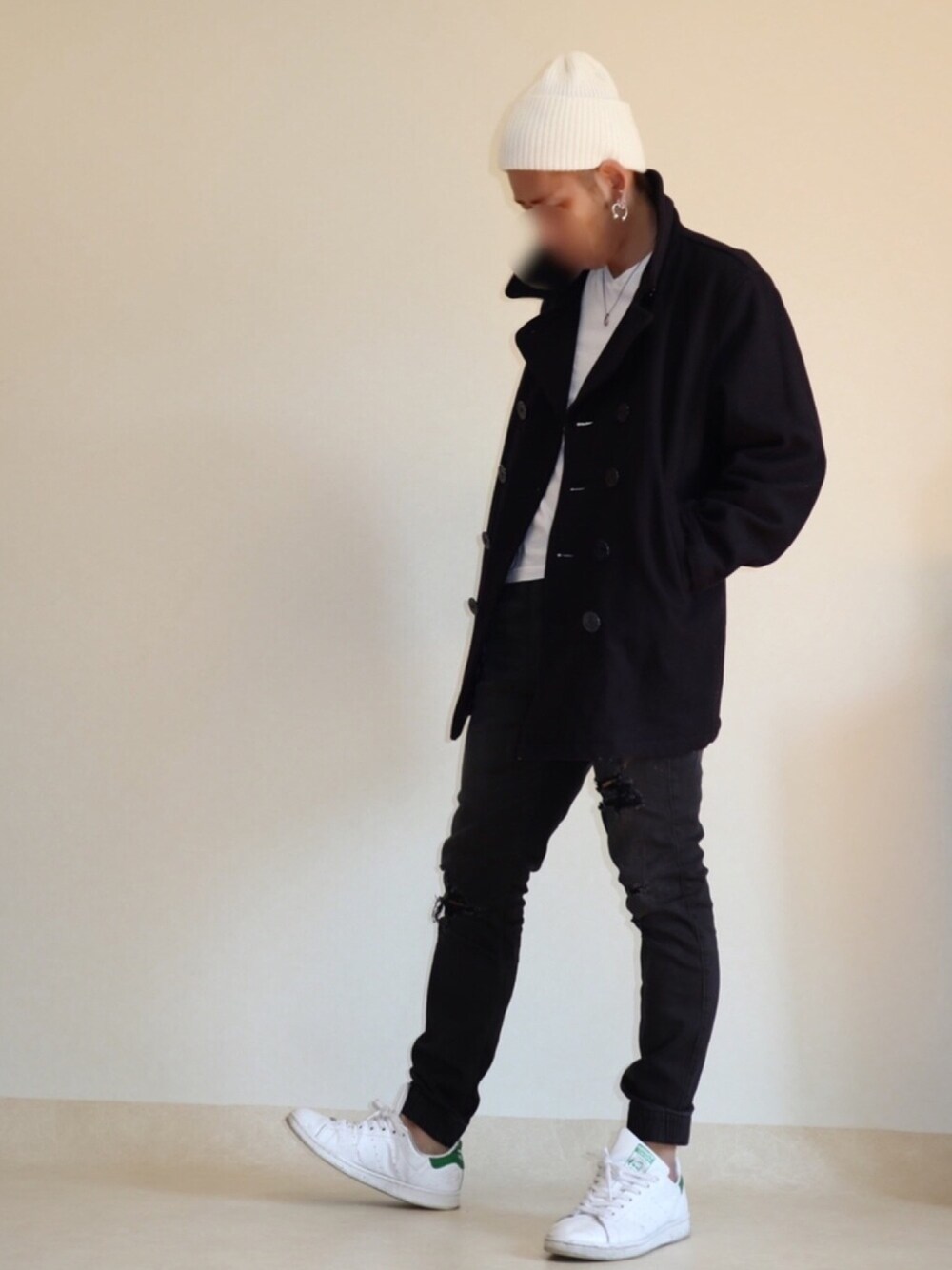 ブラック系のピーコート、ブラック系のデニムパンツ、ホワイト系のスニーカーを着用したメンズの春コーディネートの1枚目の写真