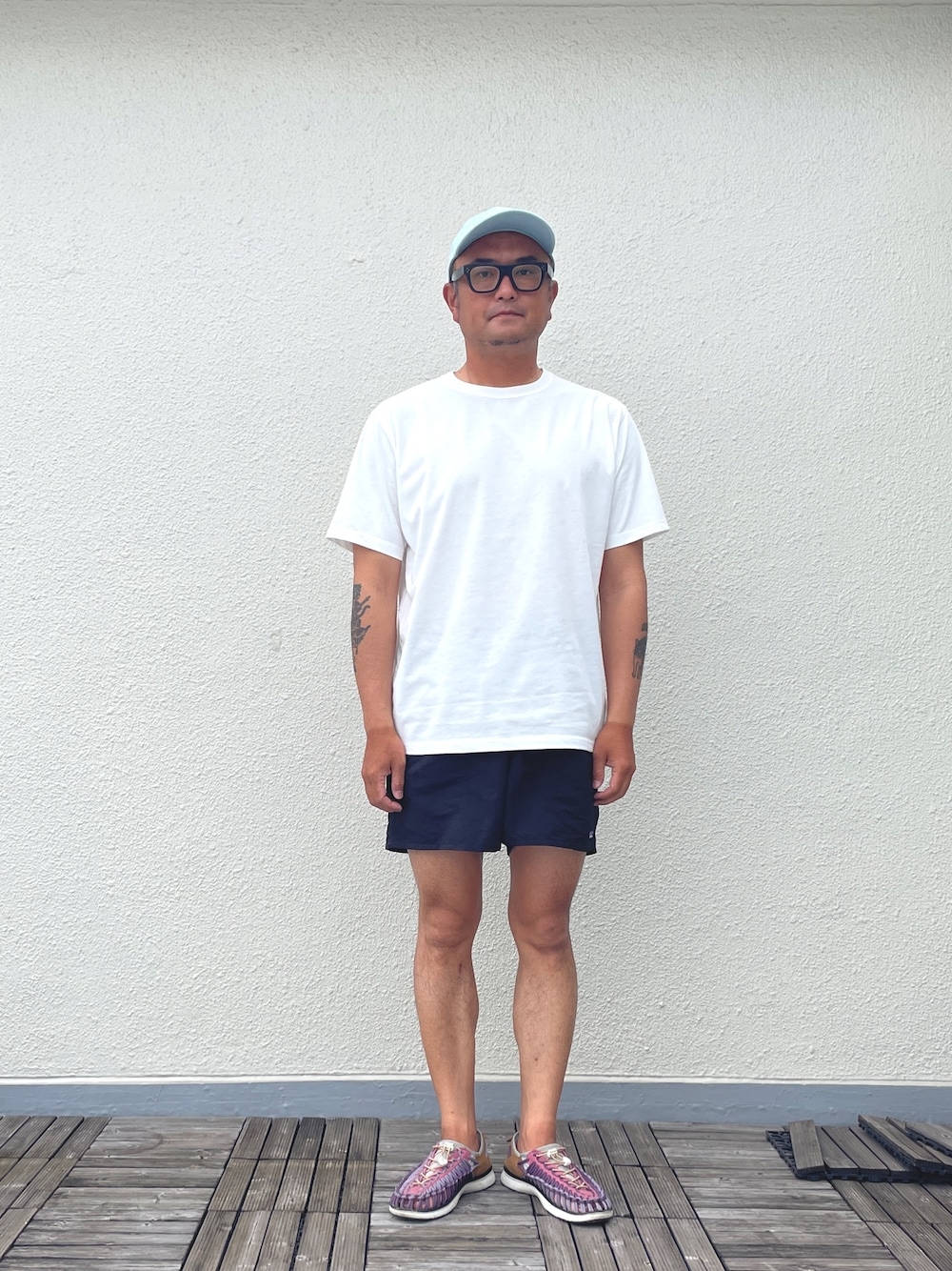 ホワイト系のTシャツ/カットソー、ブラック系のパンツ、パープル系のサンダルを着用したメンズの夏コーディネートの1枚目の写真